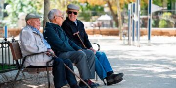 Tres jubilados conversan sentados en un banco de un parque tras la subida de pensiones que eleva el IRPF en 2025