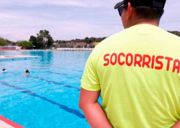 Socorrista con camiseta amarilla supervisa una piscina al aire libre en Madrid, cerrada por falta de personal durante la ola de calor